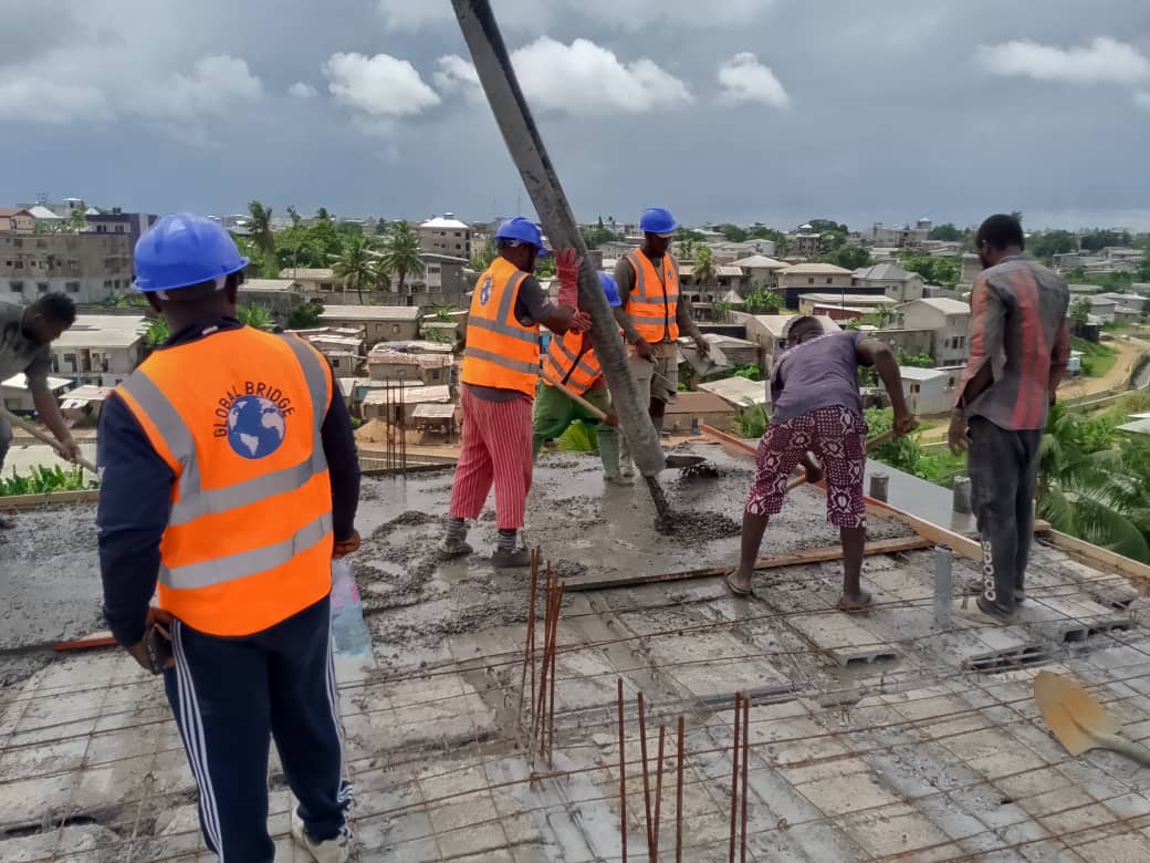 Construction workers pouring concrete slab in Cameroon by Global Bridge Group